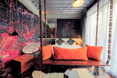 a bedroom with a bed with orange pillows and a bench at MeStyle Garage Hotel in Bangkok