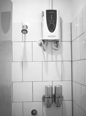 a white tiled bathroom with a soap dispenser on the wall at Bangkok Sanookdee Hostel in Bangkok