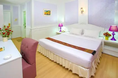 a bedroom with a large white bed and a chair at PJ Watergate Hotel in Bangkok