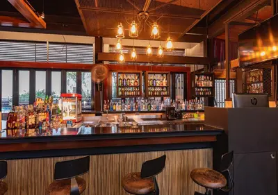 a bar with chairs and a counter with alcohol at D&D Inn Khaosan in Bangkok