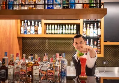 a man standing behind a bar holding a drink at D&D Inn Khaosan in Bangkok