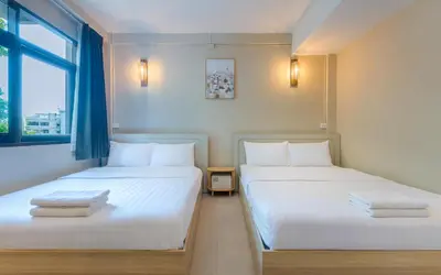 two twin beds in a room with a window at At Hua Lamphong Hotel in Bangkok