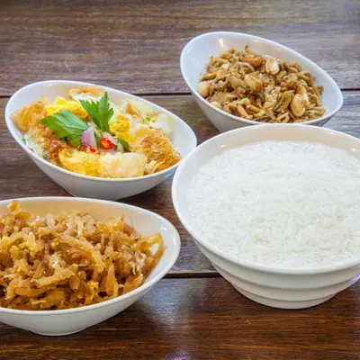 a table with four bowls of food and rice at At Hua Lamphong Hotel in Bangkok