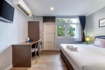 a hotel room with a bed and a desk at At Hua Lamphong Hotel in Bangkok