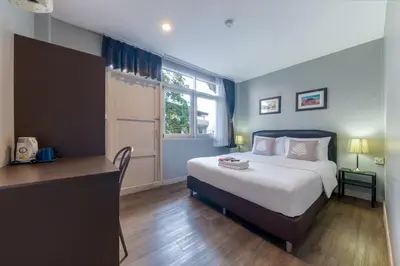 a bedroom with a bed and a desk and a window at At Hua Lamphong Hotel in Bangkok