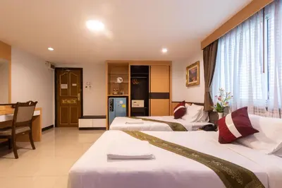 a hotel room with three beds and a desk at Gusto Pratunam Hotel in Bangkok