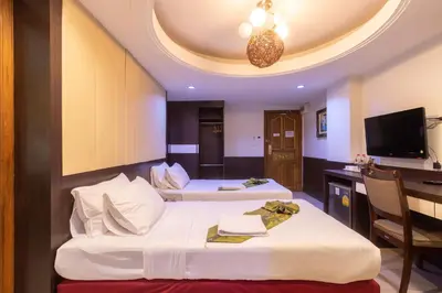 a hotel room with two beds and a desk at Gusto Pratunam Hotel in Bangkok