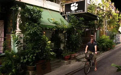 a man riding a bike down a street at Born Free Hostel in Bangkok
