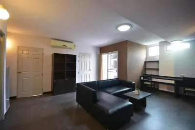 a living room with a black couch and a piano at LOFT Salaya in Salaya