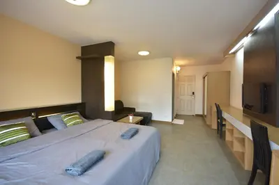 a bedroom with a large bed and a flat screen tv at LOFT Salaya in Salaya