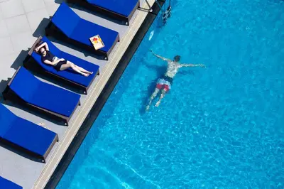 a man is swimming in a swimming pool at Lasalle Suites Hotel & Residence in Bangkok
