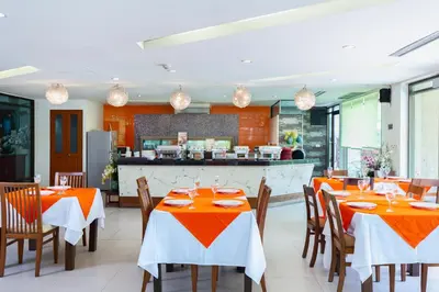 a restaurant with orange tables and chairs and a kitchen at Lasalle Suites Hotel & Residence in Bangkok