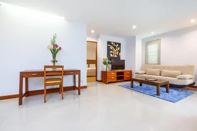 a living room with a desk and a couch at Lasalle Suites Hotel & Residence in Bangkok