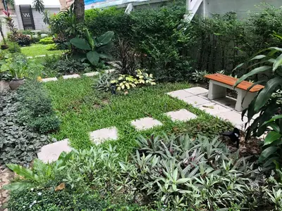 a garden with a bench sitting on the grass at M. Swita เอ็ม.สวิต in Bangkok