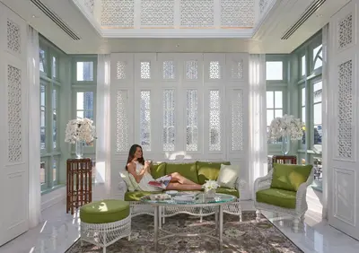 a woman sitting on a couch in a living room at Mandarin Oriental, Bangkok in Bangkok