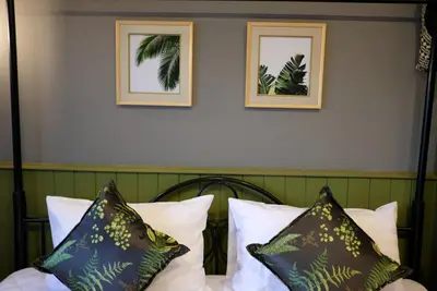 a bed with pillows and two framed pictures on the wall at TANA CASA 12 Large Sathorn 6BR Townhome with Parking in Bangkok