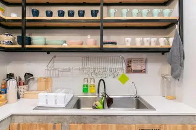 a kitchen with a sink and a shelf with dishes at Timber Hostel in Bangkok