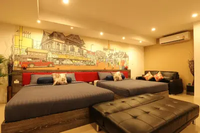 a room with two beds and a couch and a painting at Serena Sathorn Suites in Bangkok