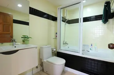 a bathroom with a toilet and a sink and a tub at Serena Sathorn Suites in Bangkok