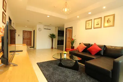 a living room with a black leather couch and a table at Serena Sathorn Suites in Bangkok