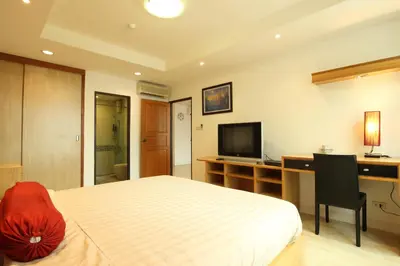 a bedroom with a bed and a desk and a television at Serena Sathorn Suites in Bangkok