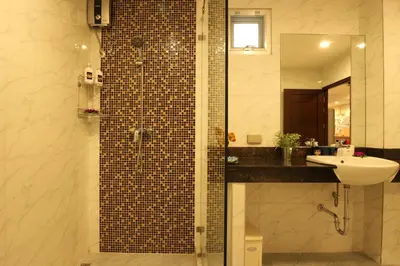 a bathroom with a sink and a shower with a mirror at Serena Sathorn Suites in Bangkok