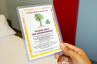 a person holding up a sign that reads please help the environment at Vib Best Western Sanam Pao in Bangkok