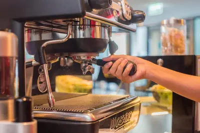 a person is preparing food in a coffee machine at Vib Best Western Sanam Pao in Bangkok