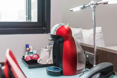 a red and black mixer sitting on a desk next to a bed at Vib Best Western Sanam Pao in Bangkok