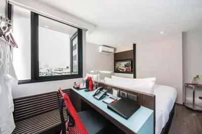 a bedroom with a bed and a desk with a phone at Vib Best Western Sanam Pao in Bangkok