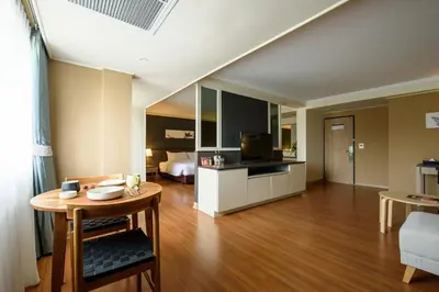 a living room with a table and a room with a bed at SC Park Hotel in Bangkok