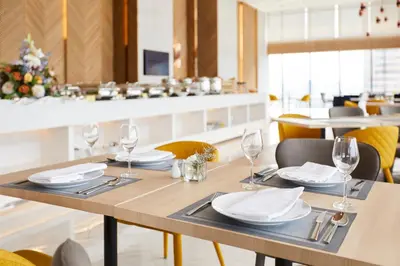 a dining room with a table with plates and wine glasses at The Quarter Ari by UHG in Bangkok