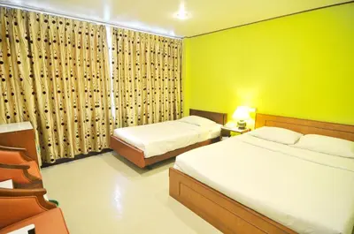 a bedroom with two beds and a green wall at Malaysia Hotel Bangkok in Bangkok