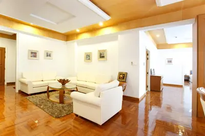 a living room with white couches and a table at Chaidee Mansion in Bangkok