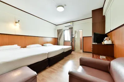 a hotel room with two beds and a couch at Nice Palace Hotel in Bangkok