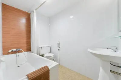 a bathroom with a tub and a toilet and a sink at Nice Palace Hotel in Bangkok