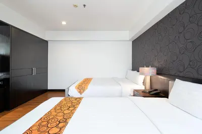 a hotel room with two beds and a wall at Lily Hotel Bangkok in Bangkok