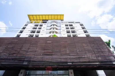 a tall white building with a yellow roof at Lily Hotel Bangkok in Bangkok