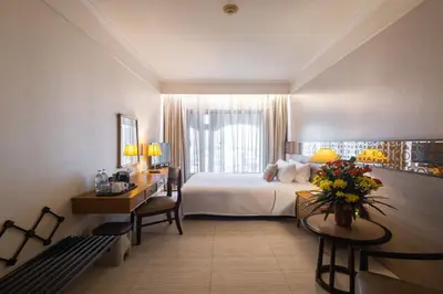 a hotel room with a bed and a table and a desk at Indra Regent Hotel in Bangkok