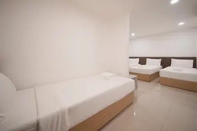 a white room with two beds and two couches at Grand Alpine Hotel in Bangkok
