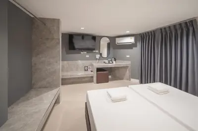 a bathroom with two white tables and a television at Grand Alpine Hotel in Bangkok