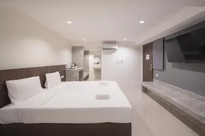 a bedroom with a large white bed and a flat screen tv at Grand Alpine Hotel in Bangkok