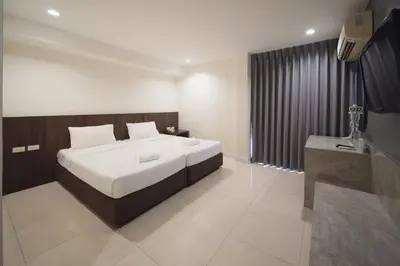 a bedroom with a large white bed and a television at Grand Alpine Hotel in Bangkok
