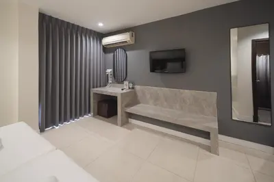 a bathroom with a bench and a tv in a room at Grand Alpine Hotel in Bangkok