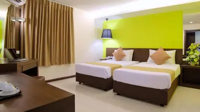 a hotel room with two beds and a desk and a computer at Grand Alpine Hotel in Bangkok