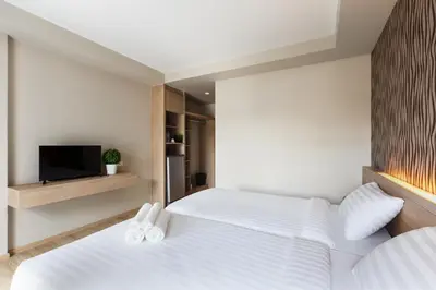 a bedroom with two beds and a flat screen tv at @S115 Residence in Samutprakarn