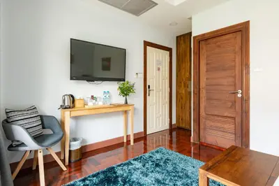 a living room with a chair and a television on a wall at Maneeya Park Residence in Bangkok