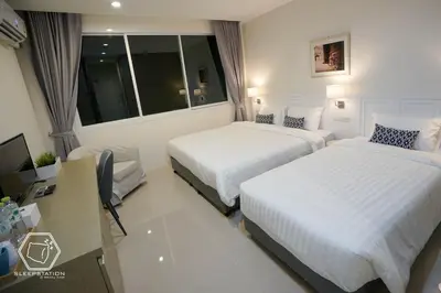 a hotel room with two beds and a desk and a window at Sleepstation at Pratunam in Bangkok