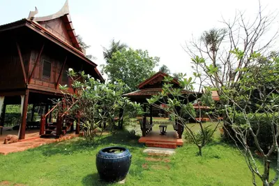 a house with a large tire in front of a yard at Dhabkwan Resort in Nonthaburi