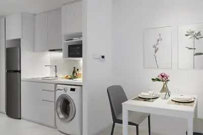 a white kitchen with a washing machine and a table at Somerset Maison Asoke Bangkok in Bangkok